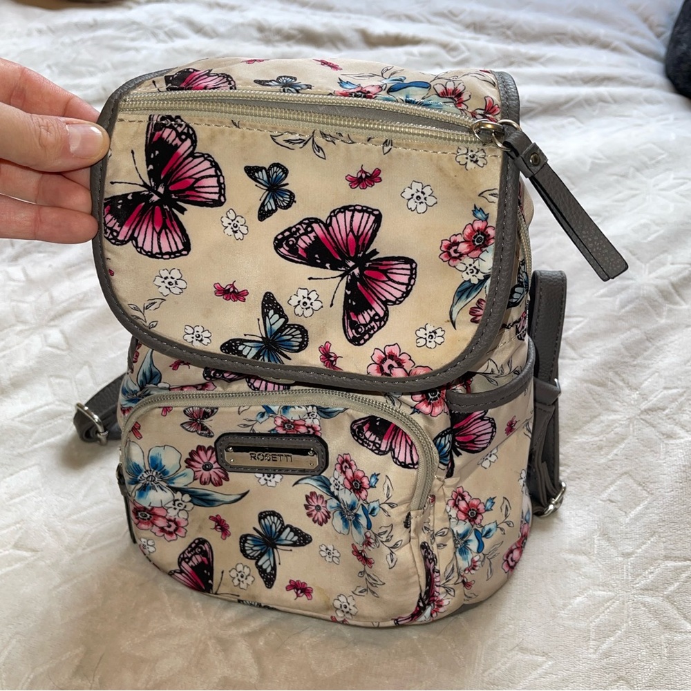 Rossetti Butterfly backpack. Two zippers and open pouch pocket. Cream color.